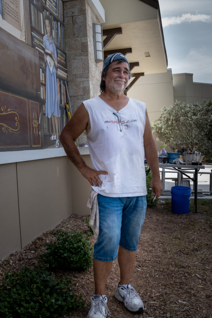 Skip Dyrda Standing in front of the Punta Gorda Library mural he painted.