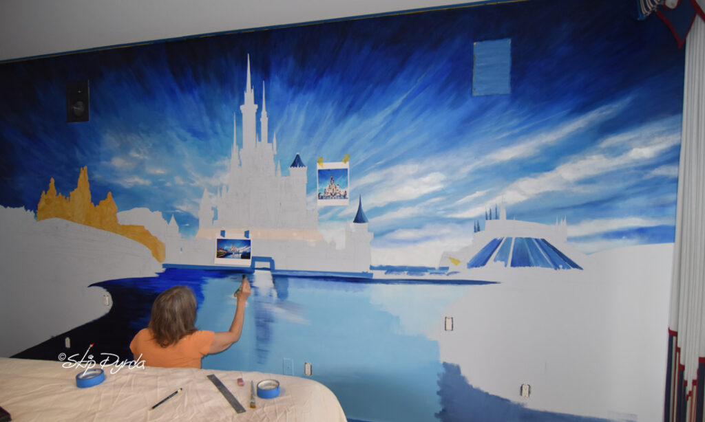 A photo of a mural I painted in a condo on Longboat Key, FL. The mural is a sort of fictional landscape of DisneyWorld. In Progress 2