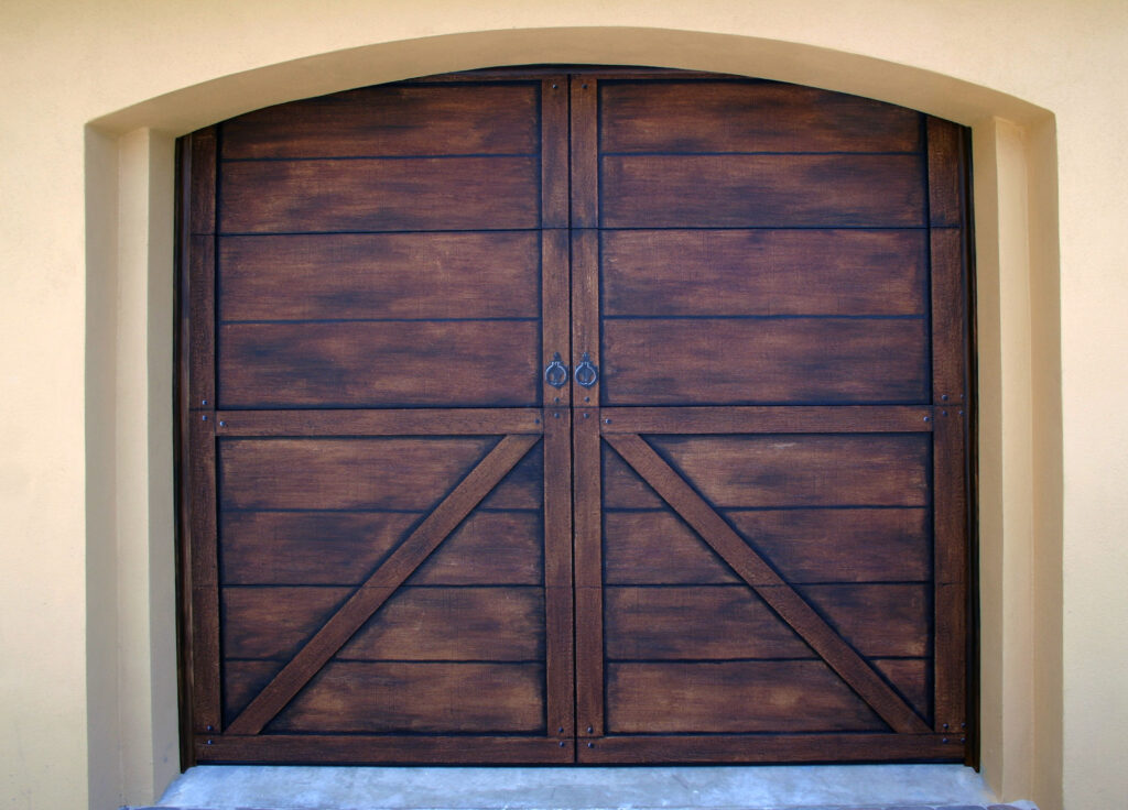 A photo of a garage door that I painted to look like old and weather wood with castiron hardware