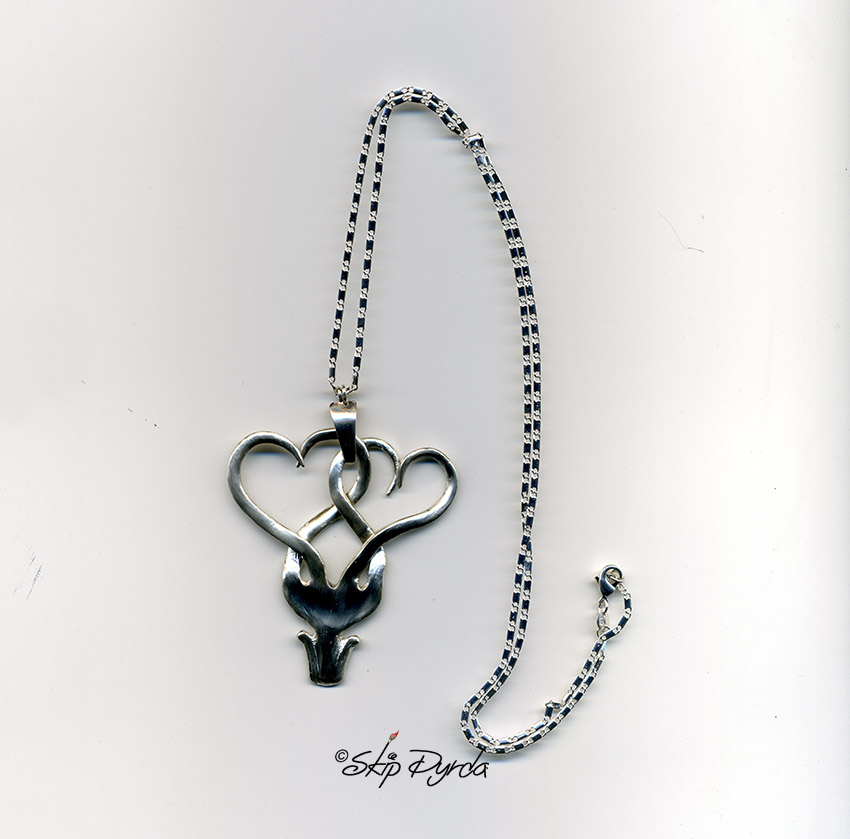 A photo of a pair of intertwined hearts, made from a stainless steel fork