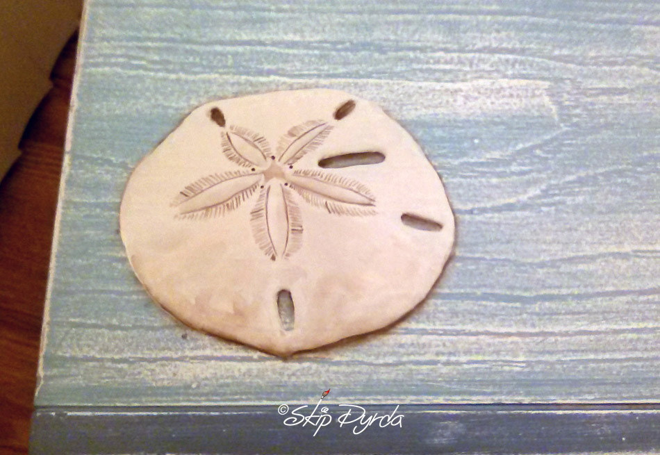 A photo of a custom painted nightstand with seashells painted on the front