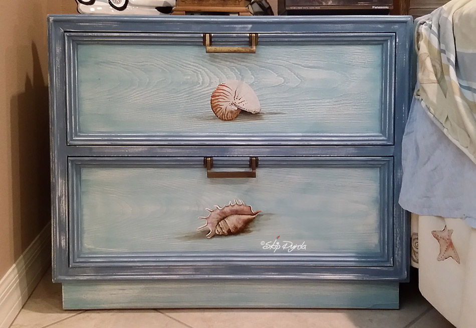 A photo of a custom painted nightstand with seashells painted on the front