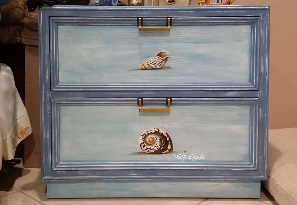 A photo of a custom painted nightstand with seashells painted on the front