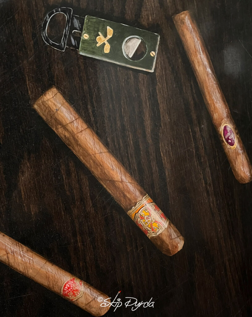 A photo of a large round coffee table that I stained and then painted over 20 Trompe L'oeil cigars on it.