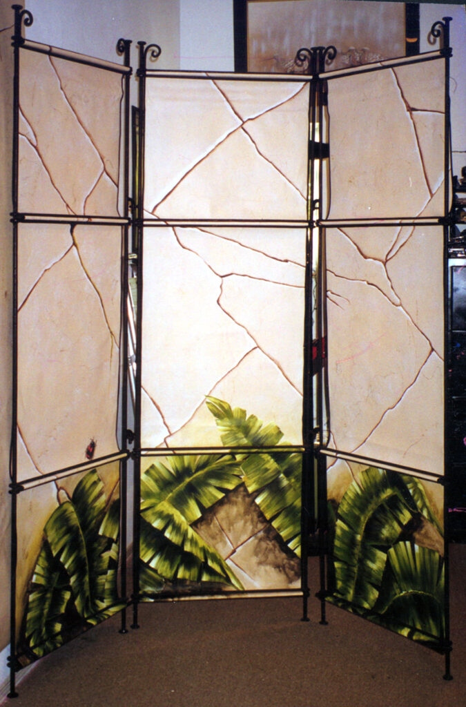 A photo of a painted canvas and steel privacy screen. I painted the canvas panels to look like stone with tropical leaves at the Bottom