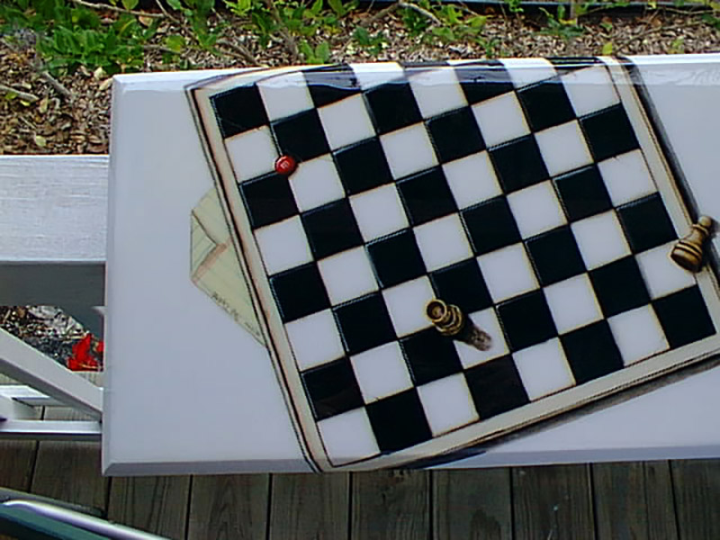 A detail photo of a sofa table on which is painted a chess board and a few chess pieces